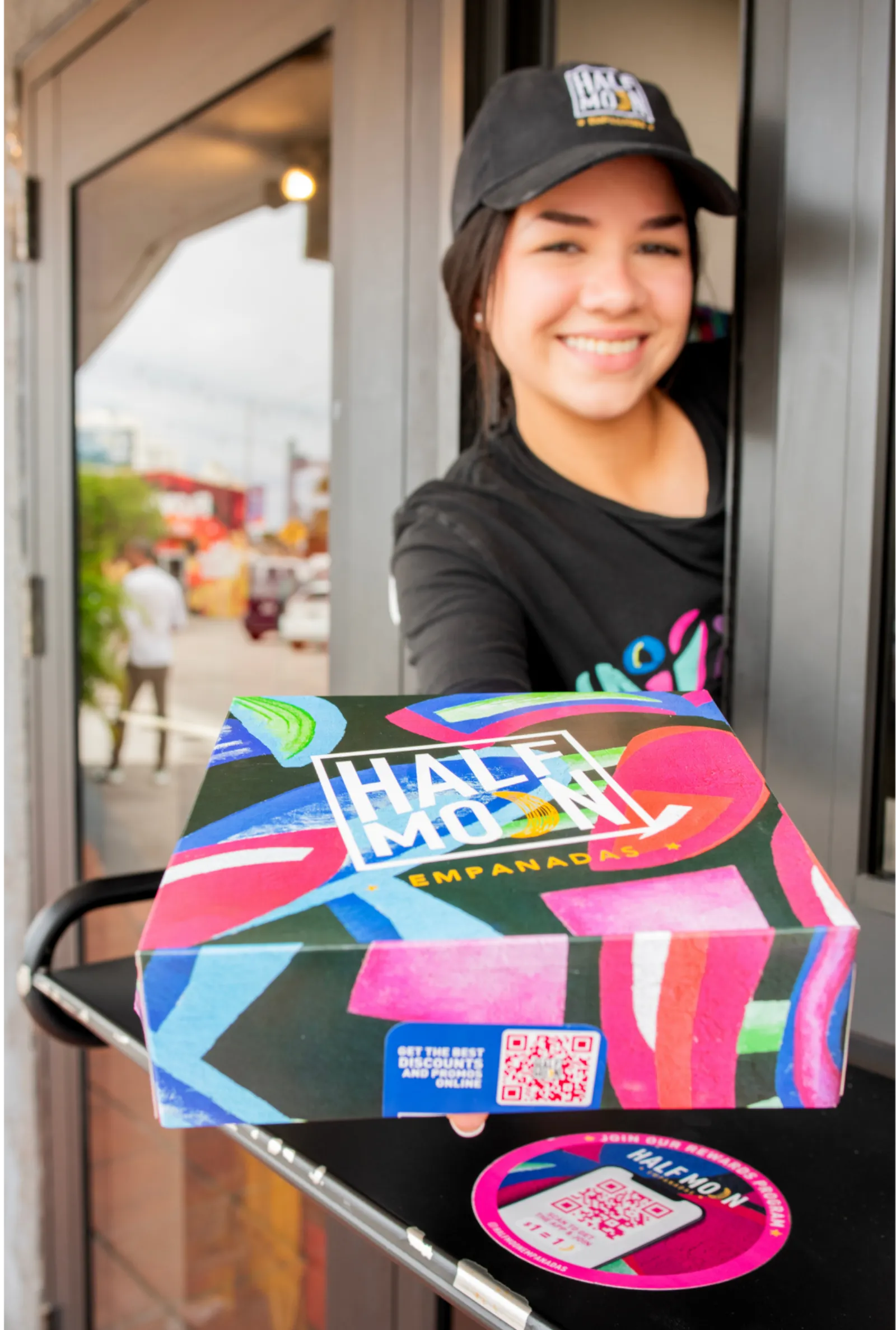 Half Moon Empanadas team member handing a box of empanadas